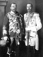 Two bearded men of identical height wear military dress uniforms emblazoned with medals and stand side-by-side