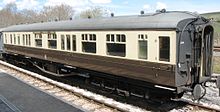 A long coach with domed roof ends. The roof is pale grey and ends black. The body has brown lower parts but cream above around the windows.