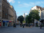 Zona comercial Fargate, de Sheffield. Una vez que una carretera muy transitada, se ha peatonal durante varias décadas y es la principal zona comercial City Centre de Sheffield, el hogar de muchas empresas de renombre. La imagen muestra la arquitectura clásica en ambos lados con un plan de espacios en el centro, salpicado de árboles y los edificios de la calle son visibles más allá de los árboles.