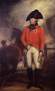 Hombre bien afeitado vistiendo la chaqueta roja de un general del ejército británico 1800 con la estrella de la Orden de la Jarretera, calzones blancos, botas altas negras y un sombrero bicornio negro. Detrás de él, un novio tiene un caballo.