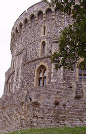 Una fotografía que muestra el lado izquierdo de una torre circular de piedra de piedra gris y con pequeñas ventanas.