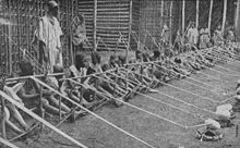 Una fila de más de una docena de niños tomados de telares de madera se extiende en la distancia.