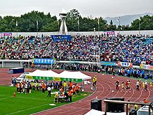 La gente animando a sus equipos con banderas de colores de pista y campo de juegos en un estadio