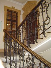 Escalera ornamentada, un aterrizaje con una puerta interior y ventana, escalera continua hasta