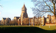 Un plano general de una vieja escuela de Inglés con una torre central, un campo deportivo se ve en primer plano.