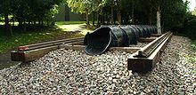 Exterior en el bosque. una sección corta de la línea de ferrocarril sobre traviesas de madera con una tubería de hierro fundido de aproximadamente el diámetro de pie, corriendo en línea con los rieles