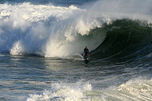 Foto de la persona que practica surf en la parte inferior de la ola, tratando de dejar tubo envolverlo