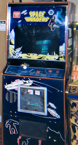 Une borne d'arcade bleu avec un ??cran entour?? de d??calcomanies. Les contr??les de jeu sont assis en dessous de l'??cran, tandis que la phrase