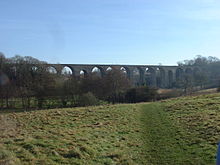 viaduc en pierre avec plusieurs arches, en partie masqu??e par tress