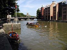 Un taxi jaune sur l'eau entre quais de pierre. La banque a bien grands b??timents et la distance est un pont ?? trois arc.