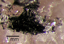 Une masse sombre, ?? environ 2 millim??tres de diam??tre, sur un substrat de cristal de couleur rose