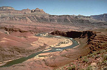 Rocher brun fonc?? couches dans le mod??le stairstep dans corniches au-dessus d'une rivi??re dans un canyon de rouge et de la roche expos??e tan