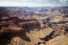 Grand canyon avec abruptes parois de couleur beige. Une rivi??re dans une vall??e est sous une surface en pente douce large.