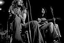 Une photographie en noir et blanc de Robert Plant avec un tambourin et Jimmy Page avec une guitare acoustique assis et performant