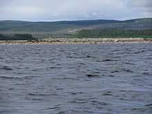 Sur le cours de la rivière Caniapiscau en été, on voit des pierres dans une partie du lit à la surface.