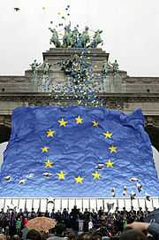 Photo montrant des ballons s'envolant devant le drapeau européen et un arc de triomphe à Bruxelles.