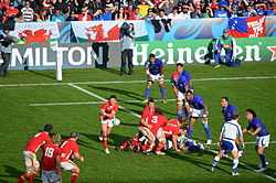 Photographie d'un match de rugby à XV entre le pays de Galles en maillots rouges et les Samoa en maillots bleus
