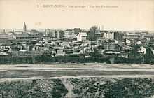 Carte postale en noir et blanc. Au premier plan, l'espace vide des fortifications, en arrière, le bidonville de la Zone