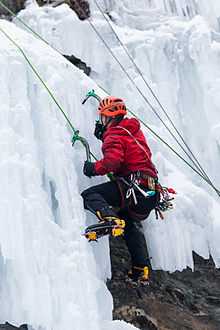 Un grimpeur grimpant une cascade de glace avec piolets et crampons