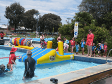 Des enfants et parents dans une piscine publique à ciel ouvert, toutes et tous avec un t-shirt filtrant les rayons ultraviolets