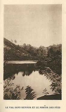 Une forêt et une colline qui se reflètent dans les eaux d'un lac.