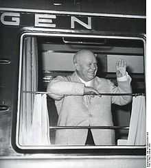 Photographie d'un homme souriant saluant depuis la fenètre d'un wagon