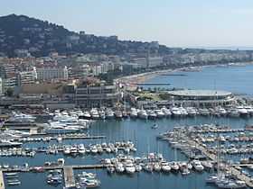 Au premier plan, le Vieux-Port de Cannes, le coin des pêcheurs, au pied du village historique du Suquet; Palais des festivals et au fond La Croisette et son célèbre hôtel Carlton