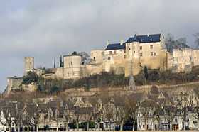 Photographie d'un château aux murs blancs au sommet d'une colline avec une ville en contrebas