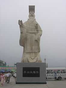 Photographie d'une statue haute d'environ 9 mètres, qui représente Qin Shihuang levant la main droite.