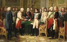 Peinture représentant, dans un intérieur richement décoré, dont trois fauteuils rouges à sphinx dorés, une foule entourant trois personnages au centre. On reconnait à droite Napoléon, uniforme blanc aux manches noires, bottes de cuir noir et ceint d'une écharpe bleu clair ; il porte plusieurs décorations sur le cœur. Il fait face à un officier aux cheveux blancs et courts, en uniforme blanc sur pantalon rouge, ceint d'une écharpe dorée et botté en cuir noir. Il s'incline légèrement en tendant un papier roulé à Napoléon, qui tend le bras pour le prendre. Au second plan, une table sur laquelle se trouve une nappe verte, derrière laquelle se trouve un personnage de face, aux cheveux blancs et longs, en uniforme noir ceint d'une écharpe rouge, portant plusieurs décorations.