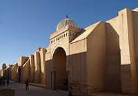 Photographie montrant les porches et les contreforts de la façade occidentale. Le porche de Bab al-Gharbi (au centre de l’image) est coiffé d’une coupole blanche côtelée.