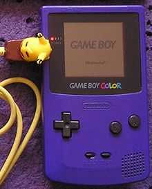 Photo d'une Game Boy mauve avec un câble link jaune en forme de Pikachu.