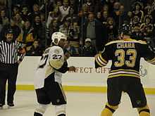 Photo de Georges Laraque et Zdeno Chara poings levés, prêts à se battre, sous les regards du public et d'un arbitre.