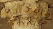 Photographie d’un chapiteau en pierre à figures animales, localisé à l’intérieur du portique occidental de la cour. Il est orné de bustes de bœuf.