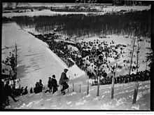 Photographie en noir et blanc d'un tremplin de saut à ski vu en plongée.