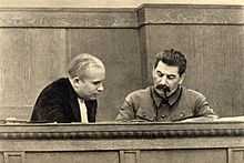 Photographie de deux hommes étudiant des documents sur un bureau.