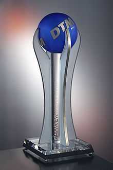 Photographie d'un trophée allongé gros, avec une boule bleue en haut, avec inscrit DTM