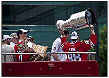 Photographie montrant Patrick Kane qui brandit la Coupe Stanley et Jonathan Toews qui tient le trophée Conn-Smythe.