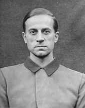 Photo noir et blanc (format photo d’identité, en buste, de face) de Karl Brandt, médecin SS de Hitler. L’homme porte une veste claire au col foncé fermé.