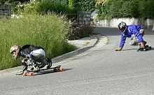 Deux personnes faisant du longboard descendant une route ici en virage.