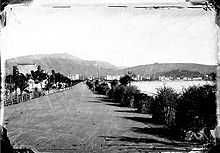 Photo abîmée du XIXe siècle orientée est de la promenade des Anglais avec la mer à droite et les collines en fond.