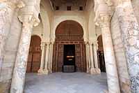 Photographie montrant la porte la plus grande et la plus ornée de la salle de prière. Renouvelée en 1828-1829, sa décoration est composée de motifs géométriques et végétaux, de moulures, ainsi que d’inscriptions en relief.