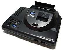 Photo d'une Mega Drive surmontée d'un boitier permettant de lire des cartouches de jeux Master System