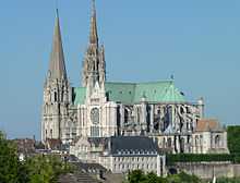 Photographie d'une cathédrale aux toits de couleur verte avec deux clochers de style différent