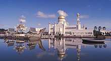 Vue de la mosquée Omar Ali Saifuddin depuis le lac. Un navire de cérémonie est accosté près de l'édifice.