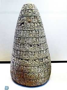 Photo verticale d'une stèle en forme de cône, gravée d'inscriptions