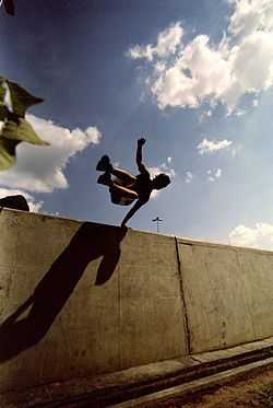 Un pratiquant de parkour au cours d'un saut « passement rapide » au-dessus d'un muret