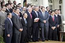 Assemblée sur plusieurs rangs posant pour les journaliste, le président Bush, au centre, tenant un ballon.