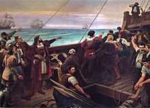 A painting depicting the deck of a wooden sailing ship on which stands a group of men pointing toward the horizon and with the sails of several other ships visible in the background