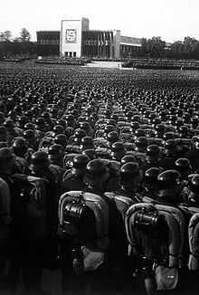 Photo noir et blanc montrant des centaines de soldats allemands, en uniforme et casqués, en train d’assister à un meeting du Parti nazi, le 9 novembre 1935 à Nuremberg.